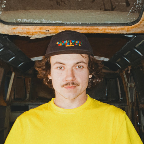 Man wearing black Old Volkswagens Ruined My Life embroidered cap inside a split bus VW van – vansofvw
