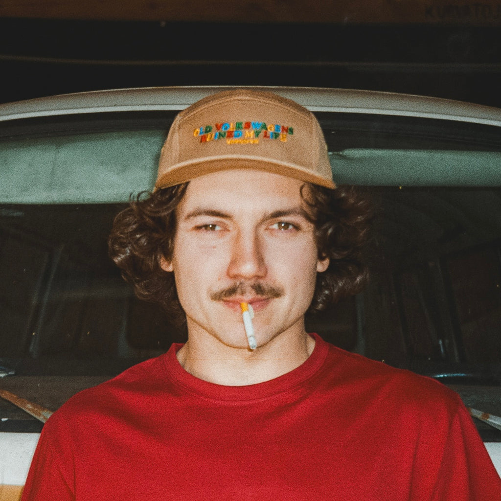 Man wearing khaki Old Volkswagens Ruined My Life embroidered cap in front of a classic Volkswagen – vansofvw
